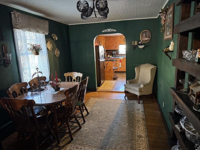 dining area featuring wood-type flooring and crown molding