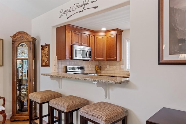 31 Shaker Hill Rd Unit 31, Hooksett, NH 03106 - kitchen featuring stainless steel microwave, range, a breakfast bar, and tasteful backsplash