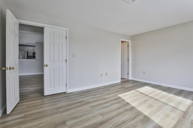 interior space featuring light wood-type flooring, baseboards, and a textured ceiling