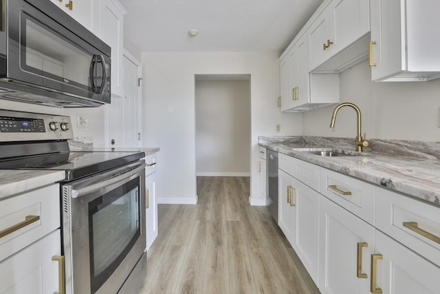 kitchen with light stone countertops, light wood-type flooring, appliances with stainless steel finishes, white cabinetry, and a sink