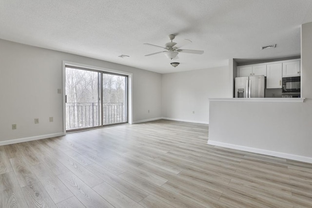 unfurnished living room featuring a textured ceiling, visible vents, light wood finished floors, and ceiling fan