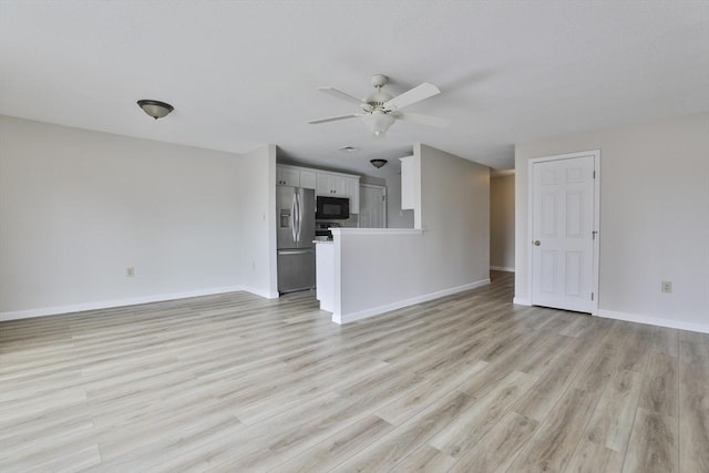 unfurnished living room featuring light wood finished floors, baseboards, and a ceiling fan