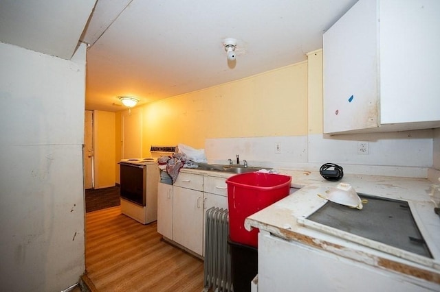 135 Elm St, Southbridge, MA 01550 - kitchen with electric range, radiator, light countertops, light wood-style flooring, and white cabinets