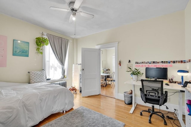 bedroom with radiator, light wood-style flooring, and a ceiling fan