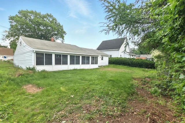 42 Jacob St, Chicopee, MA 01020 - rear view of house featuring a chimney, a lawn, and a sunroom