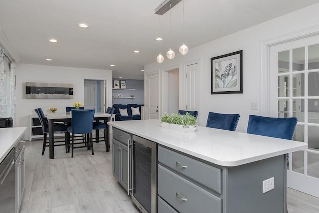 kitchen with beverage cooler, gray cabinetry, light countertops, light wood-style floors, and recessed lighting