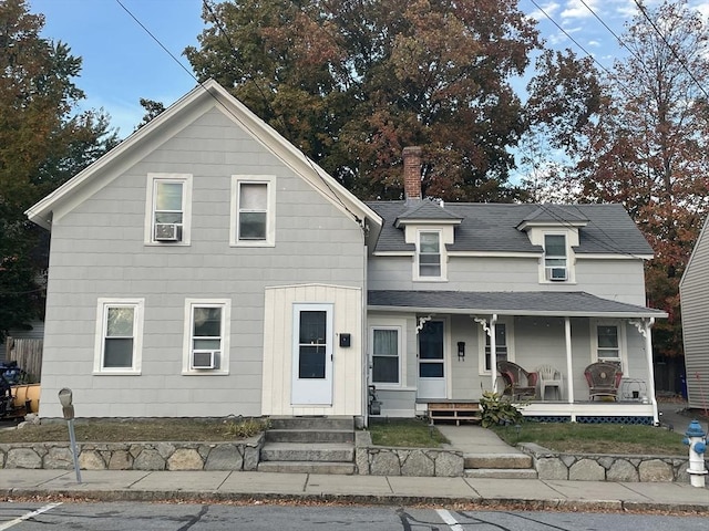 view of front of home with a porch, a chimney, and roof with shingles