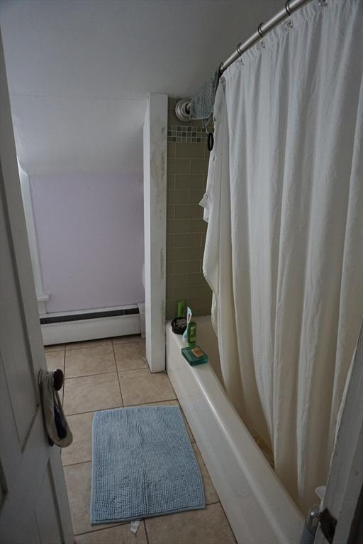 full bath featuring a baseboard radiator, tile patterned floors, and shower / bathtub combination with curtain