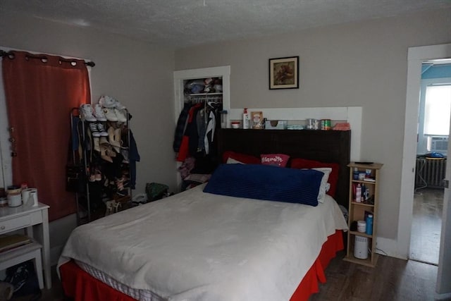 bedroom with wood finished floors, a closet, a spacious closet, a textured ceiling, and cooling unit