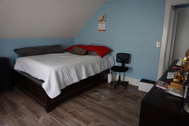 bedroom featuring wood finished floors, lofted ceiling, and baseboards