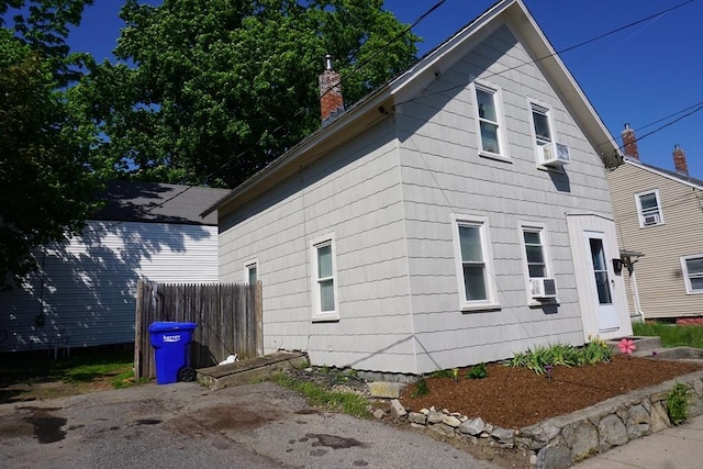 view of home's exterior featuring a chimney, fence, and cooling unit