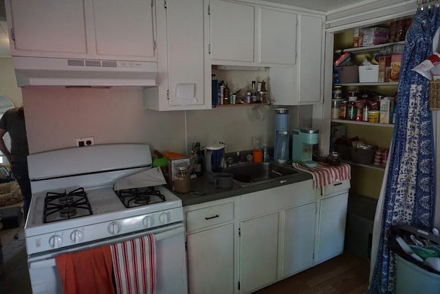 kitchen featuring under cabinet range hood, white gas range, a sink, white cabinetry, and dark wood finished floors