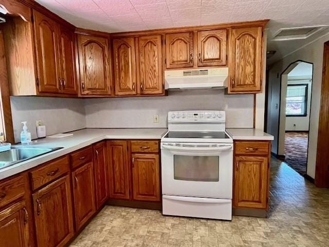 kitchen featuring white electric range, under cabinet range hood, brown cabinetry, and light countertops