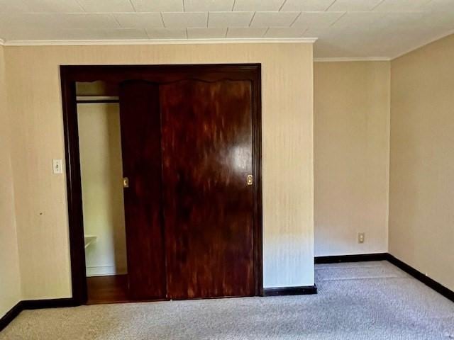 unfurnished bedroom with carpet flooring, baseboards, and ornamental molding