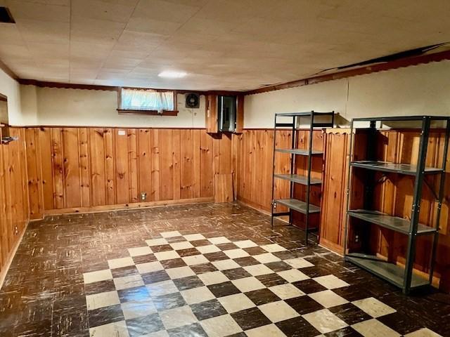 below grade area with tile patterned floors, wainscoting, and wooden walls