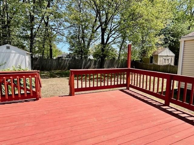 deck with a fenced backyard, a storage shed, and an outdoor structure