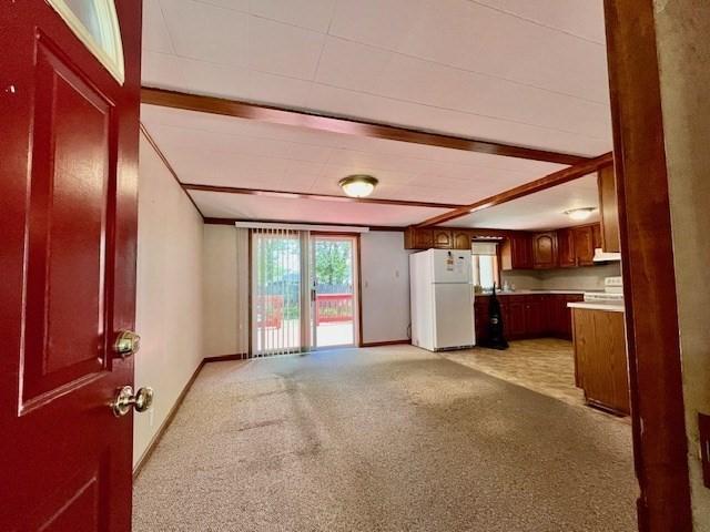 unfurnished living room featuring baseboards and light colored carpet