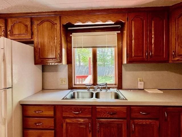 kitchen featuring a sink, freestanding refrigerator, and light countertops