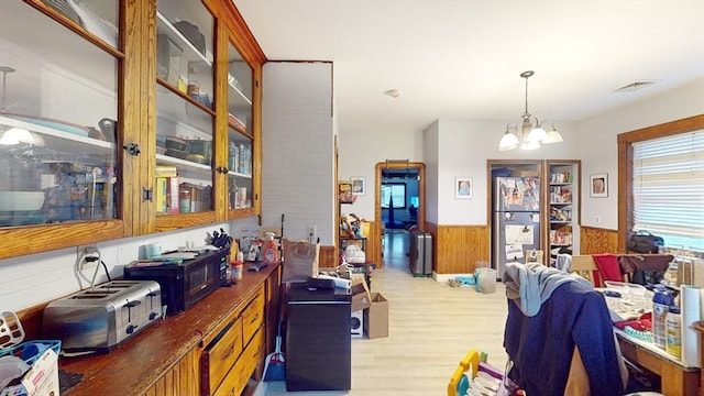 interior space with a notable chandelier, wood walls, and light hardwood / wood-style flooring