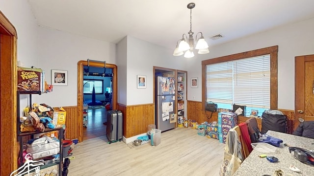 interior space featuring an inviting chandelier, wood walls, and light hardwood / wood-style floors