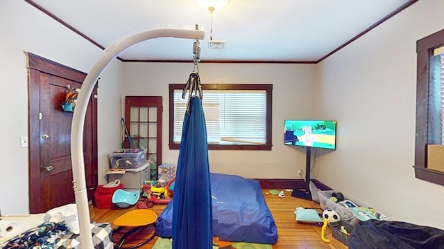 bedroom with ornamental molding and hardwood / wood-style floors