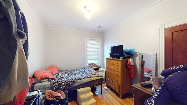 bedroom with crown molding and light hardwood / wood-style floors