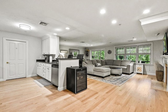 29 Maple St Unit C, Canton, MA 02021 - kitchen with stainless steel dishwasher, dark countertops, a peninsula, white cabinets, and light wood-type flooring