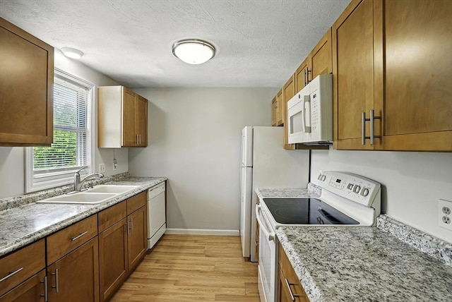 205 Bayberry Hill Ln Unit 205, Leominster, MA 01453 - kitchen featuring white appliances, light wood-style flooring, brown cabinetry, and a textured ceiling