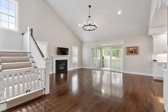 16 Dean Ln Unit 16, Littleton, MA 01460 - unfurnished living room featuring high vaulted ceiling, a chandelier, dark wood-style floors, baseboards, and a glass covered fireplace