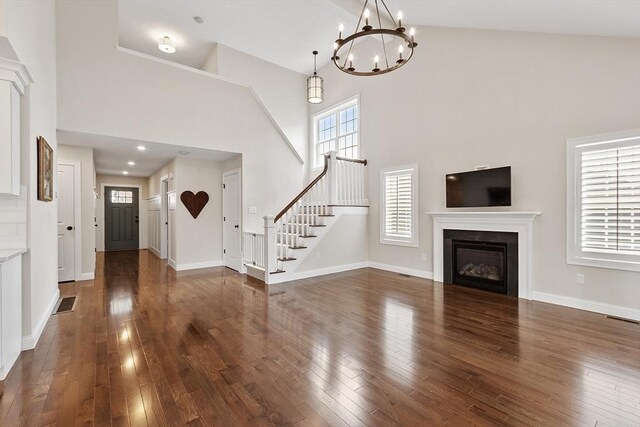 16 Dean Ln Unit 16, Littleton, MA 01460 - unfurnished living room with a towering ceiling, wood-type flooring, a chandelier, a glass covered fireplace, and stairs