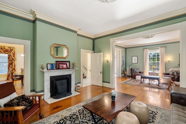 living room featuring wood-type flooring, ornamental molding, and a high end fireplace