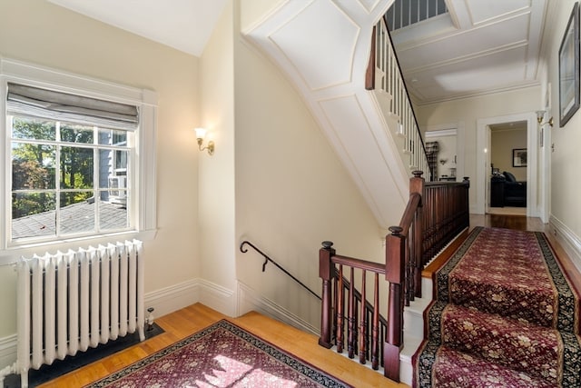 staircase with wood-type flooring and radiator heating unit