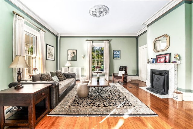 living room featuring wood-type flooring, radiator heating unit, a high end fireplace, and ornamental molding