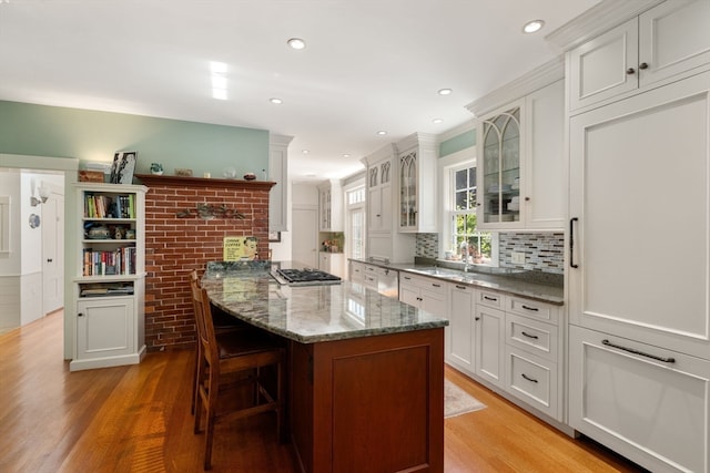 kitchen featuring stone counters, a breakfast bar area, light hardwood / wood-style flooring, and white cabinetry