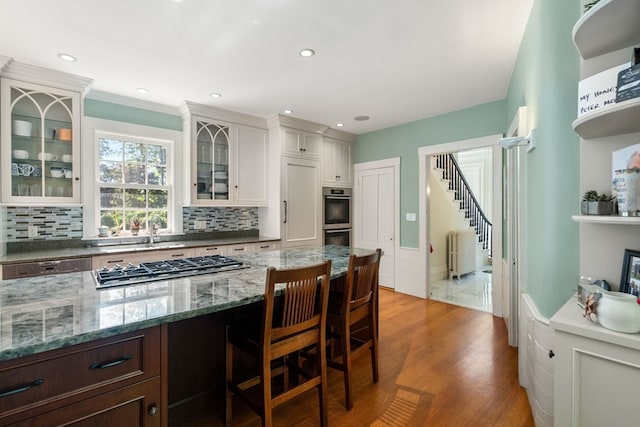 kitchen with dark brown cabinets, white cabinets, hardwood / wood-style floors, and decorative backsplash