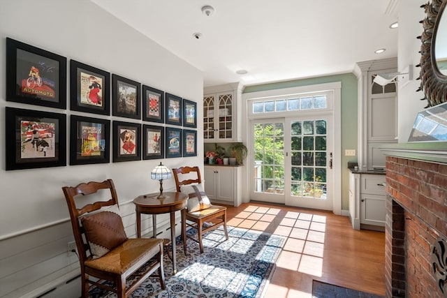 sitting room featuring a fireplace, a baseboard heating unit, and light hardwood / wood-style flooring