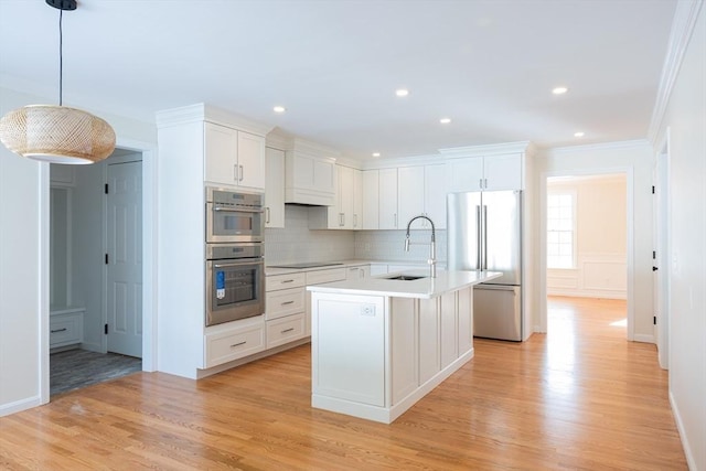 kitchen featuring stainless steel appliances, a kitchen island with sink, light countertops, and white cabinetry