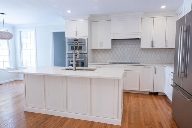 kitchen featuring stainless steel appliances, hanging light fixtures, a sink, and a kitchen island with sink