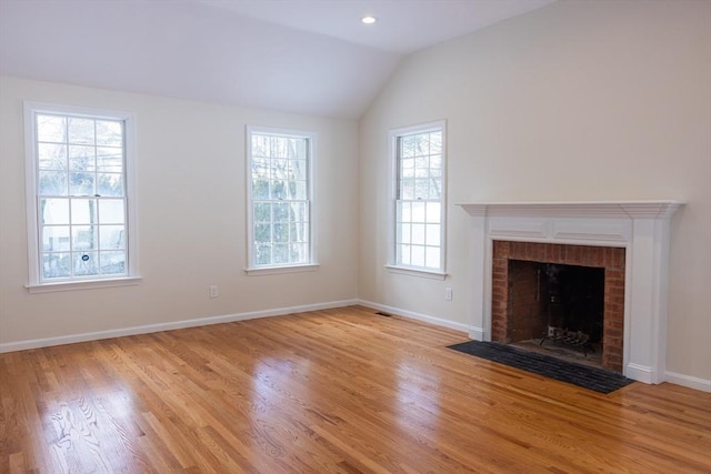 unfurnished living room with lofted ceiling, recessed lighting, a brick fireplace, light wood-type flooring, and baseboards