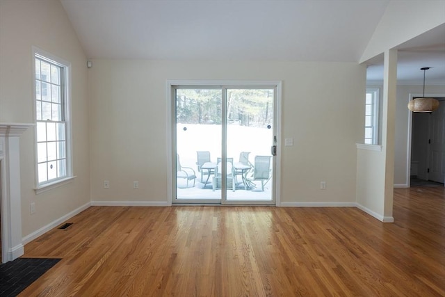 unfurnished living room with light wood-style floors, lofted ceiling, visible vents, and baseboards