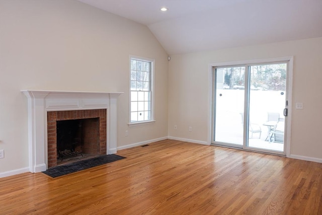 unfurnished living room featuring lofted ceiling, light wood finished floors, a brick fireplace, and baseboards