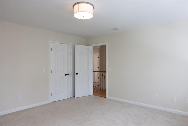 unfurnished bedroom featuring baseboards, a closet, visible vents, and light colored carpet