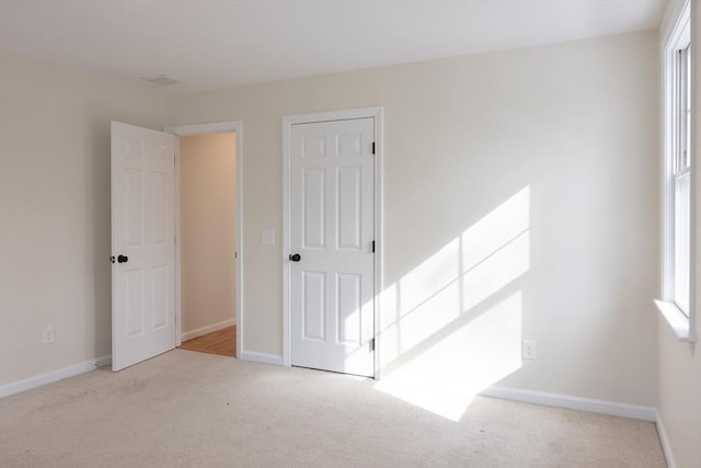 unfurnished room with baseboards and light colored carpet