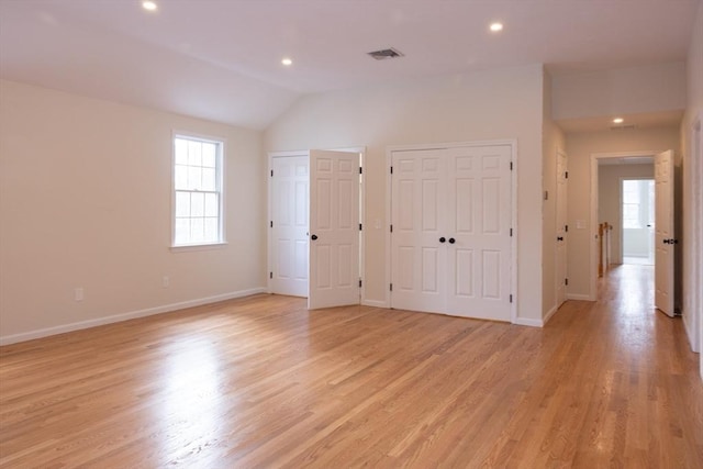 unfurnished bedroom featuring visible vents, two closets, light wood finished floors, and multiple windows