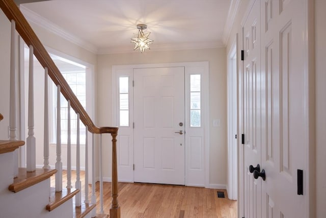 foyer with ornamental molding, stairway, light wood-style flooring, and baseboards