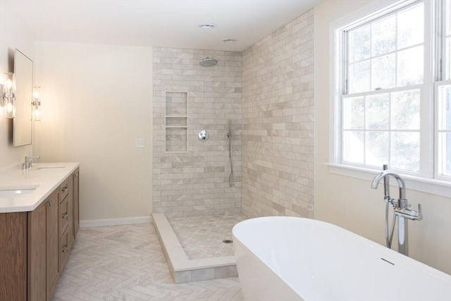 full bathroom with double vanity, baseboards, tiled shower, a freestanding tub, and a sink