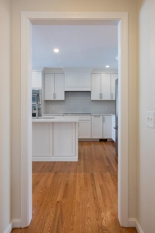 kitchen with light countertops, light wood-style floors, backsplash, and white cabinets