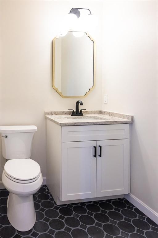 bathroom with baseboards, vanity, and toilet