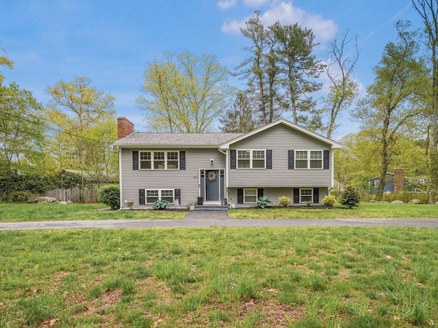 raised ranch with a chimney and a front yard