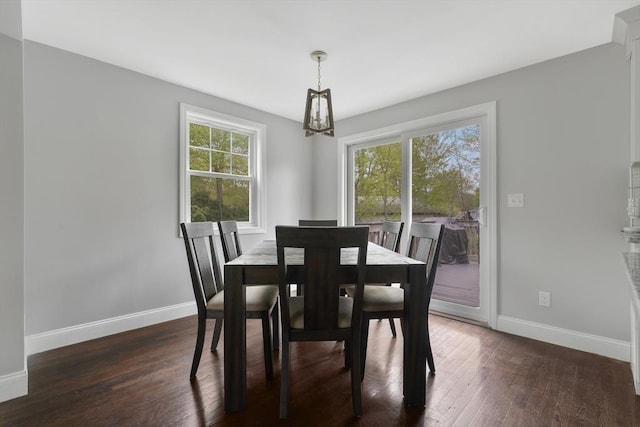 dining space with a chandelier, baseboards, and dark wood finished floors